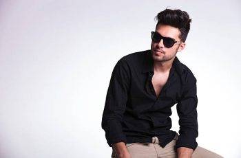 young fashion man sitting on a chair and looking away from the camera. on a light background